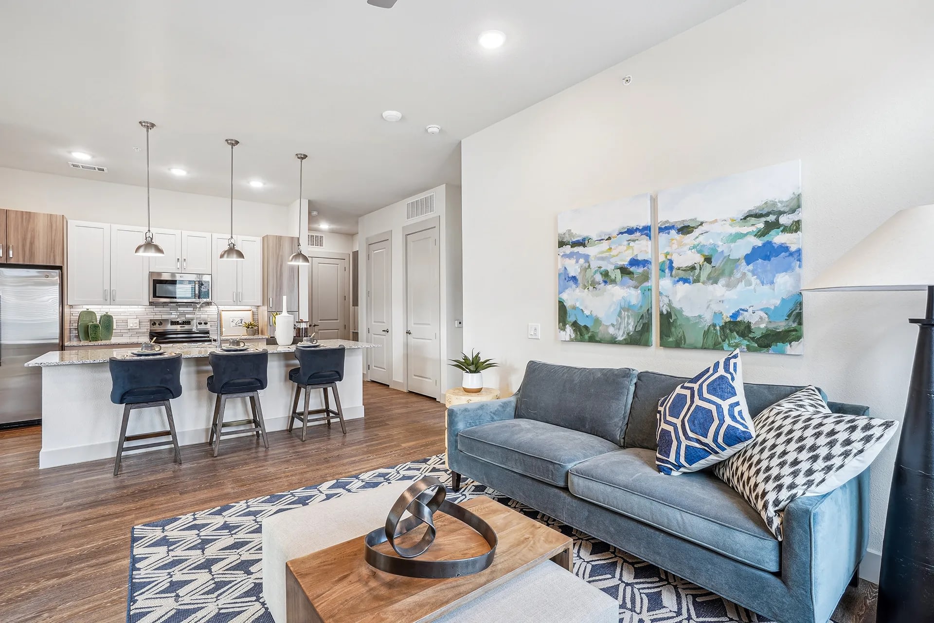 Bright living area with sofa, armchairs, and expansive windows.