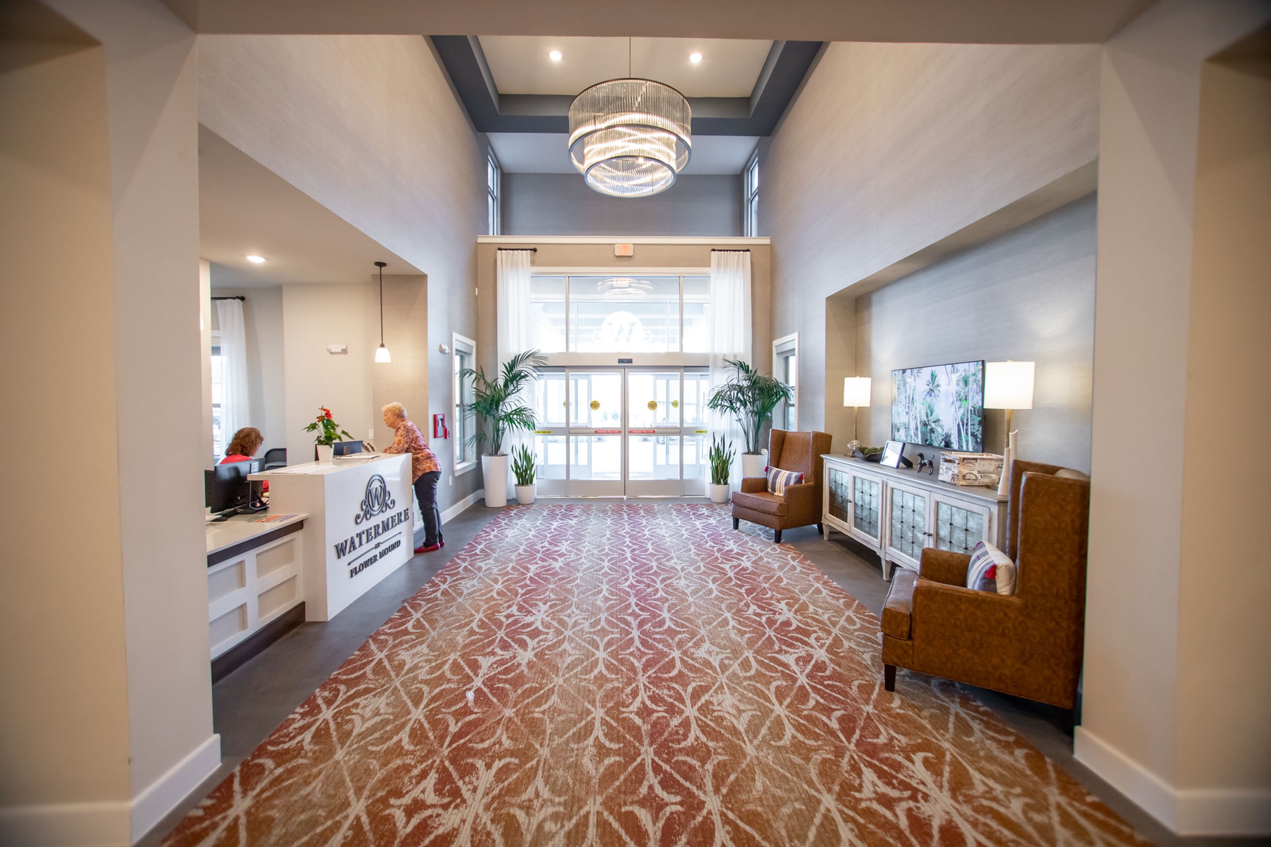 Modern hotel lobby featuring a reception desk with friendly staff, comfortable seating areas, and large windows allowing natural light. Stylish decor includes potted plants and decorative lighting, creating a welcoming atmosphere for guests.