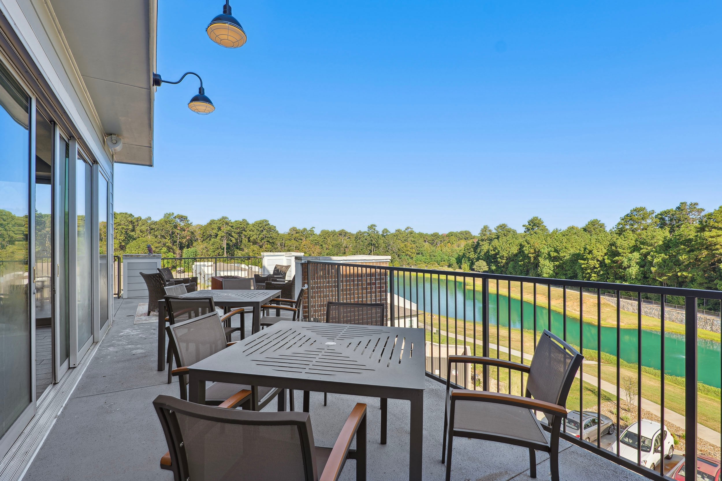 Spacious balcony with modern outdoor furniture overlooking a serene pond and lush greenery, perfect for relaxation and outdoor gatherings.