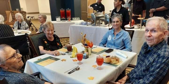 Large activity room with residents seated in a circle participating in group exercise