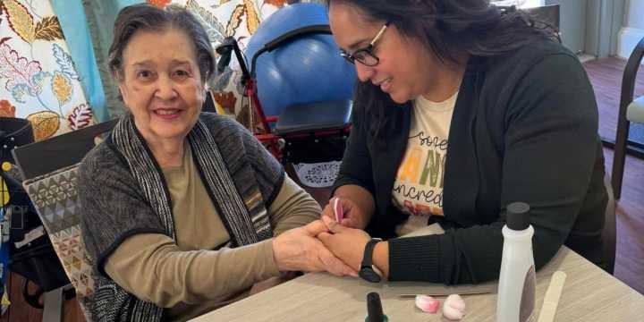 Staff member helping an elderly female resident with an activity
