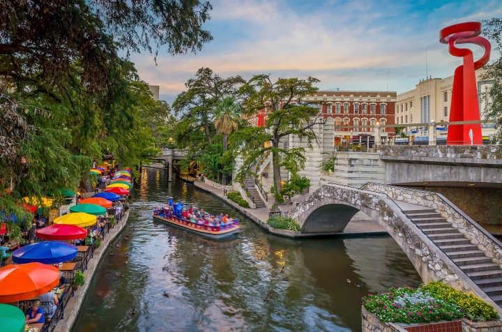 San Antonio River Walk with colorful umbrellas over outdoor dining areas and a red sculpture
