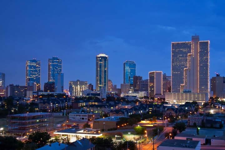 Fort Worth downtown skyline at dusk with illuminated buildings against a deep blue sky