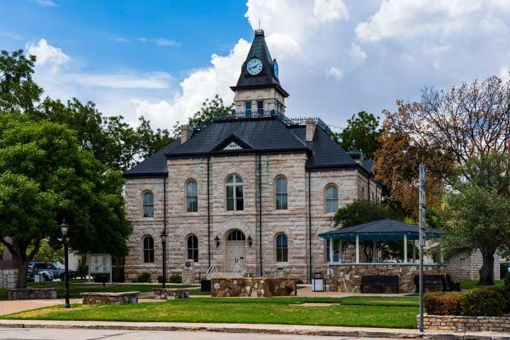 Historic Glen Rose courthouse building with clock tower against cloudy sky