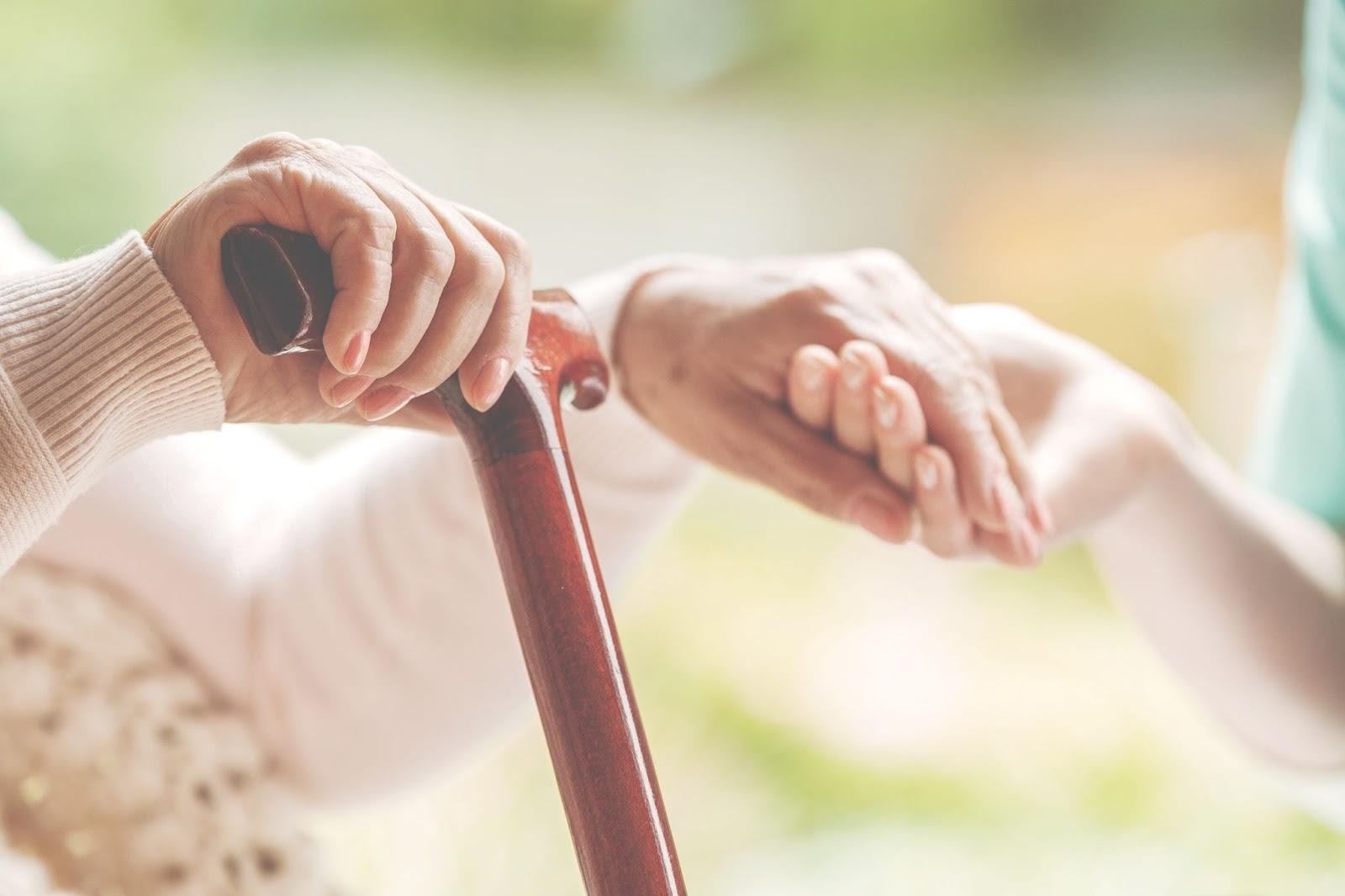 Hands reaching out over a wooden walking cane in soft lighting